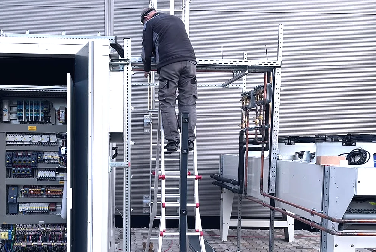 Monteur auf einer Leiter bei der Installation an einem Schaltschrank